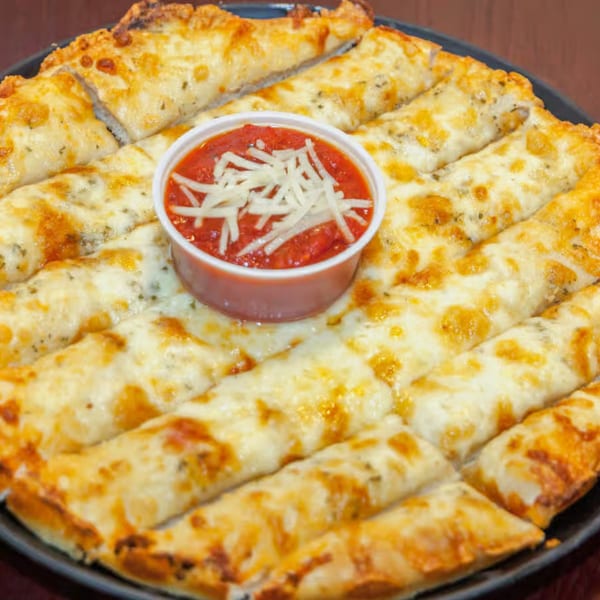 Antigoni's Pizza cheese breadsticks, golden brown and topped with herbs, served with a side of marinara.